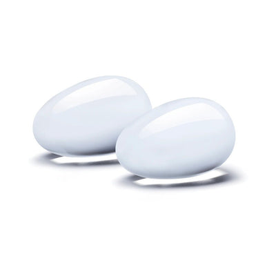 Two smooth, polished white glass yoni eggs with a teardrop shape on a white background.