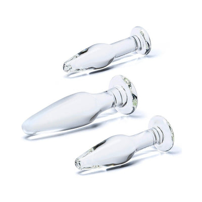 Three clear glass anal training plugs in small, medium, and large sizes with flared bases on a white background.