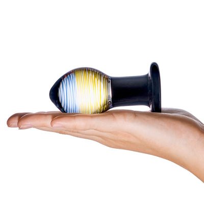 Hand holding Glas Galileo Glass Butt Plug with blue and yellow swirled bulb and black base on white background.