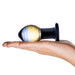 Hand holding Glas Galileo Glass Butt Plug with blue and yellow swirled bulb and black base on white background.