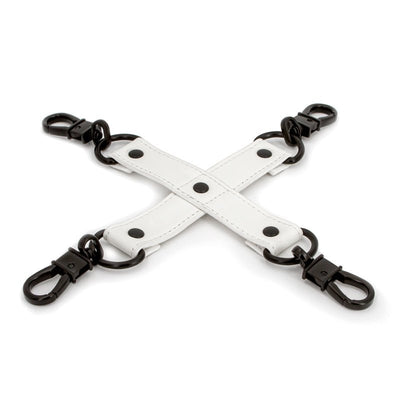 White PU leather bondage hog tie with black metal clips and rings arranged in an X shape on a white background