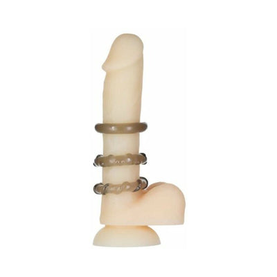 Three smoky translucent cock rings displayed on a flesh-toned silicone model with suction base.