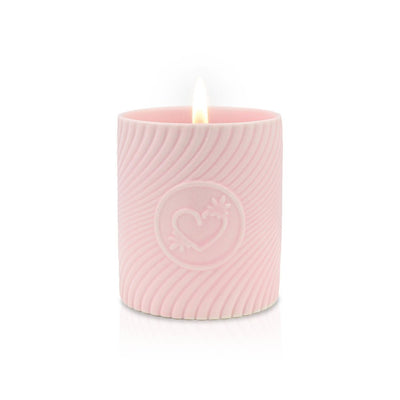 Lit pink massage candle in a textured container with embossed heart design, creating a warm, romantic ambiance.