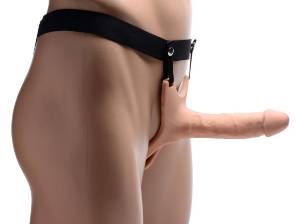 Side view of a flesh-colored hollow silicone dildo strap-on with black adjustable harness worn on a mannequin.