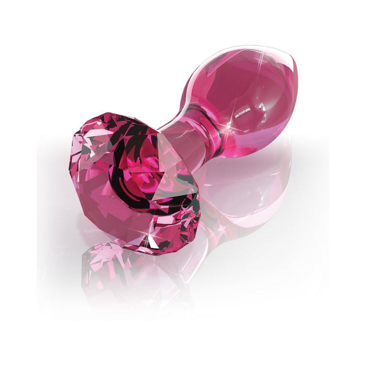 Pink hand-blown glass wand with a faceted jewel-like base and smooth rounded tip on a reflective surface.