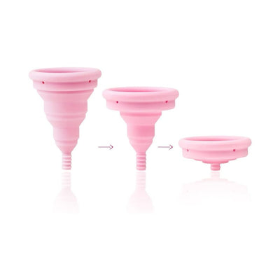 Pink Intimina Lily Cup Compact menstrual cup shown in three stages of collapsing for easy storage.