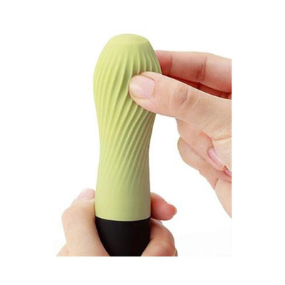 Hand holding a green tea colored Iroha Zen mini vibrator with textured silicone surface and black base.