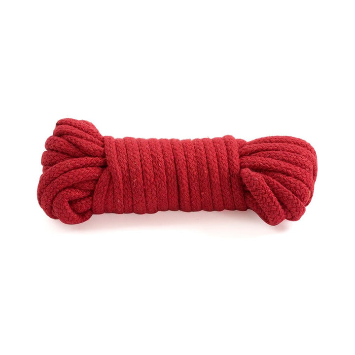 Soft red cotton Japanese style bondage rope neatly coiled on a white background.