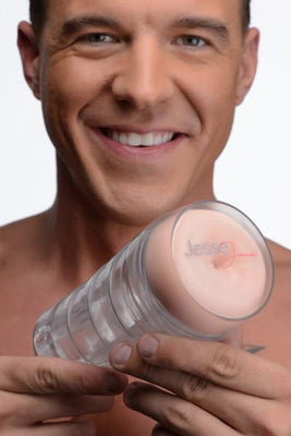 Smiling man holding a clear Jesse Jane Deluxe Ass Stroker with flesh-colored interior and logo visible on the opening.