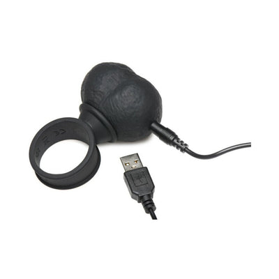 Black vibrating silicone balls with attached ring and USB charging cable on a white background.