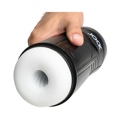 Hand holding a black and white Jock 9x rechargeable sucking and vibrating male masturbator device.