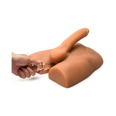 Medium tan jock ass masturbator with posable 7-inch dildo and hand holding a clear glass accessory.
