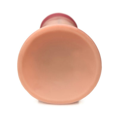 Close-up view of the suction cup base of a light-colored dual density silicone dildo.