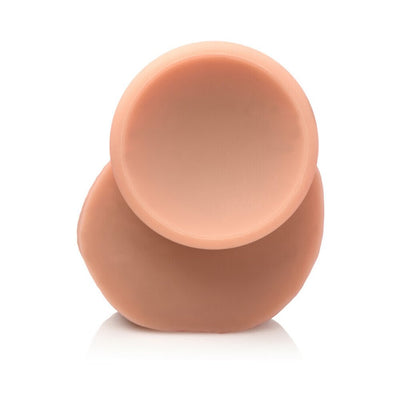 Close-up of the suction cup base of a light-colored dual density silicone dildo with balls.