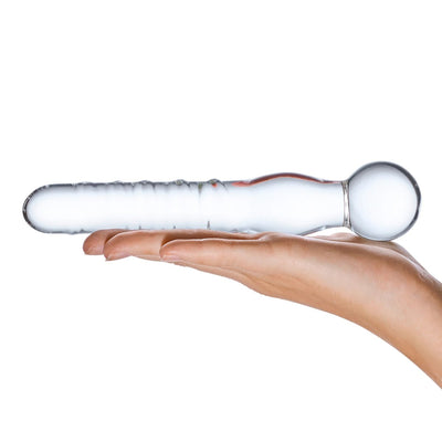 Clear glass dildo wand with spiral texture and rounded bulb end held in hand against white background.