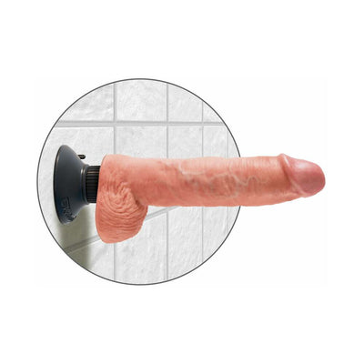 Realistic 10-inch vibrating dildo with suction cup base mounted on tiled wall in flesh tone color.