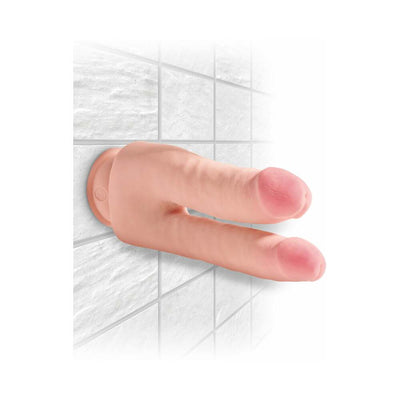 Beige double-ended dildo with realistic texture and suction cup base mounted on white tiled wall.