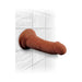 Brown realistic dildo with suction base mounted on white tiled wall, showing lifelike texture and shape.