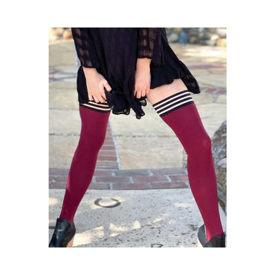 Woman wearing cranberry opaque thigh-high stockings with black and white striped tops and black dress outdoors