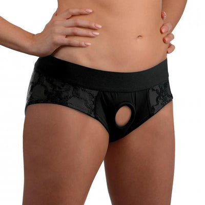 Black lace crotchless panty harness with wide elastic waistband and central O-ring detail, worn on model's hips.