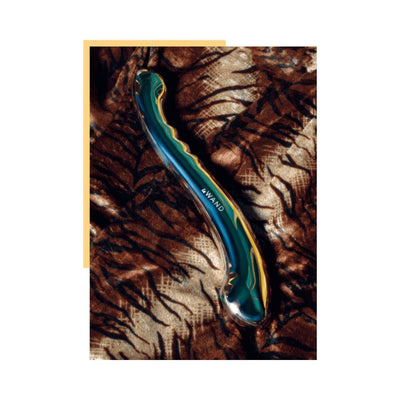 Sleek stainless steel Le Wand Contour with curved design and textured ridges on a patterned fabric background.