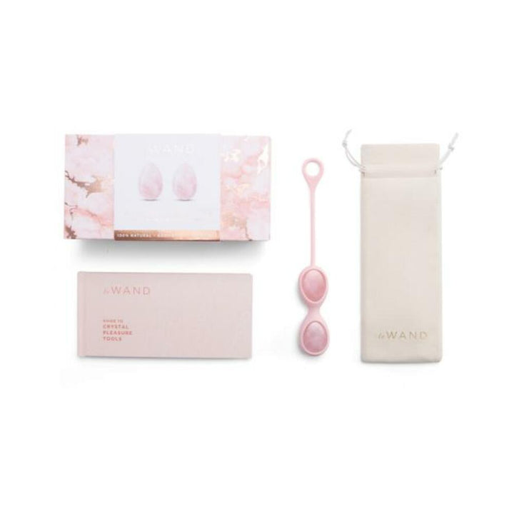 Le Wand Crystal Yoni Eggs set in rose quartz with storage pouch, guidebook, and elegant packaging on white background.