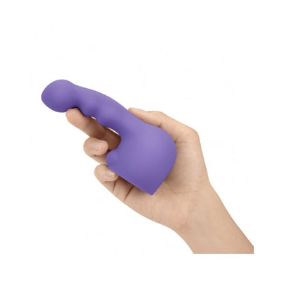 Hand holding a purple Le Wand Petite Ripple Weighted Silicone Attachment with textured, curved design.