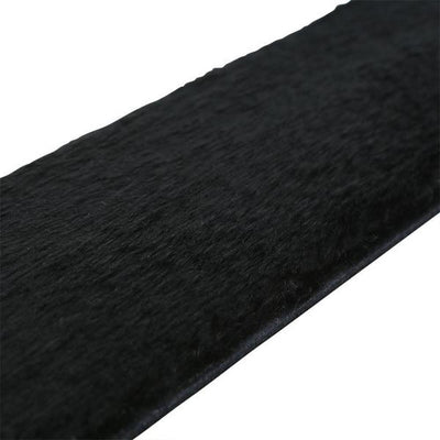 Close-up of a black leather paddle with soft black faux fur surface for dual-texture sensation.