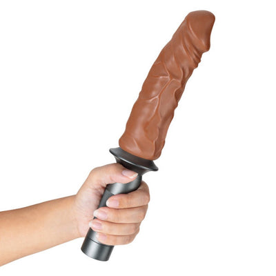 Hand holding a mocha-colored realistic dildo attached to a sleek black Karbonite Lock On handle.