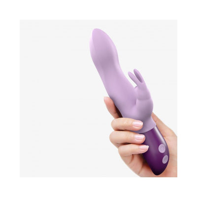 Hand holding a lavender Love To Love Hello Rabbit vibrator with dual motors and ergonomic design against a white background.