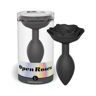 Large black silicone anal plug with an open rose design, displayed next to its clear cylindrical packaging.