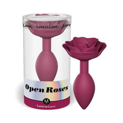Medium plum-colored anal plug with a rose-shaped base displayed next to its clear cylindrical packaging.