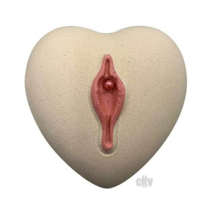 Heart-shaped beige bath bomb with a pink, stylized floral design and a small embedded pearl detail.
