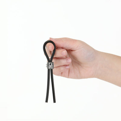 Hand holding black adjustable silicone tether with metal slider on white background