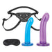 Lux Fetish beginners strap-on set with adjustable black harness, two curved silicone dildos in blue and purple, and a black blindfold.