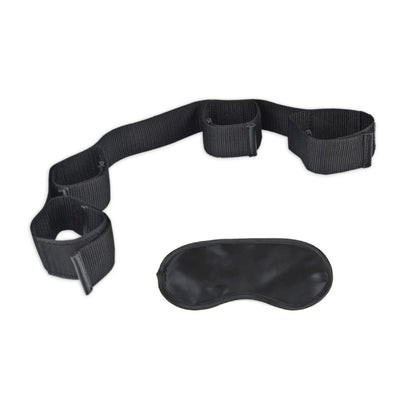 Black adjustable bondage restraint with four cuffs and a matching black blindfold on white background.