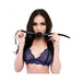 Woman in navy lace bralette holding a black silicone ball gag with adjustable strap near her mouth.