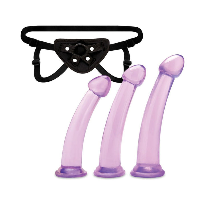 Three graduated translucent purple dildos with curved shafts and a black adjustable harness for pegging.