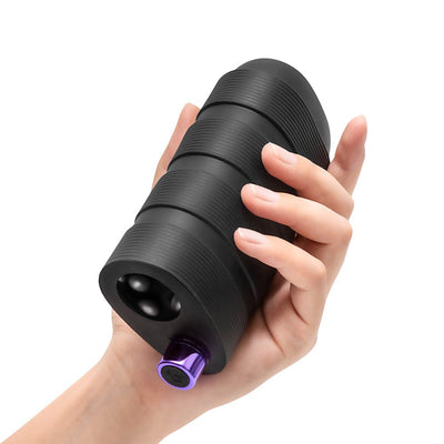 Hand holding a black textured silicone stroker with a purple control button at the base.
