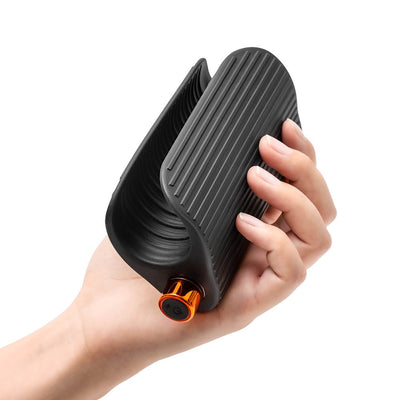 Hand holding a black ribbed silicone stroker with an orange control dial on a white background.