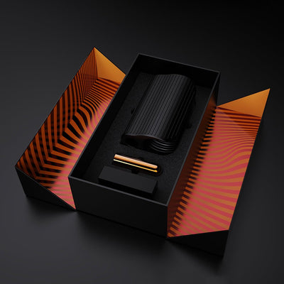 Black ribbed silicone stroker with gold bullet vibrator in sleek black and orange striped packaging box.