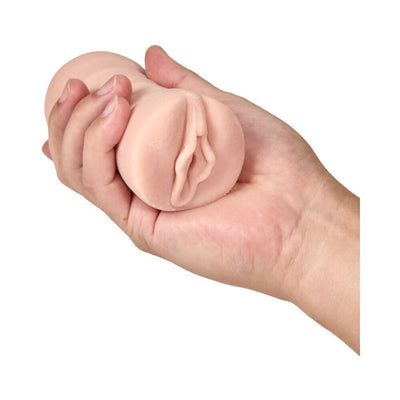 Hand holding a compact, flesh-toned, soft silicone male masturbator with a realistic vaginal design.