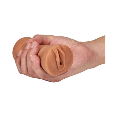 Hand holding a mocha tan M For Men Julieta soft textured vagina stroker with open-ended design.