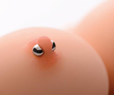 Close-up of two small, shiny magnetic orbs attached to skin, demonstrating the Magnus Mighty Magnetic Orbs product.