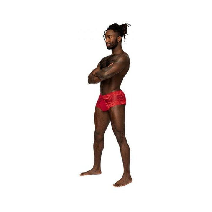 Male model wearing red lace mini shorts with sheer pouch, standing barefoot with arms crossed on white background.