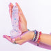 Hands holding a translucent silicone dildo with colorful confetti inside and a suction cup base.