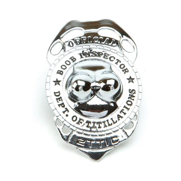 Silver-toned novelty badge with raised design and text reading Official Boob Inspector Dept. of Titillations.