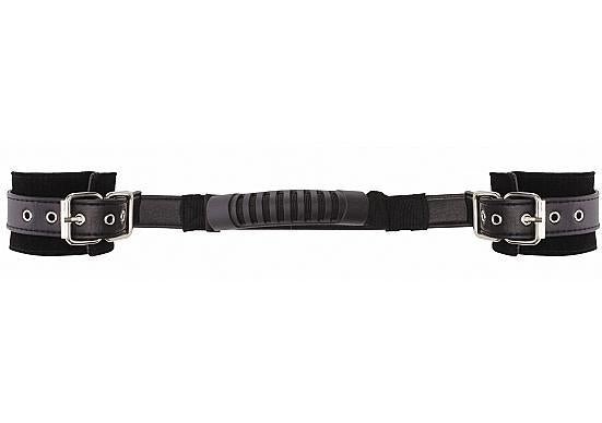 Adjustable black leather handcuffs with soft lining and a central handle for secure and comfortable restraint.