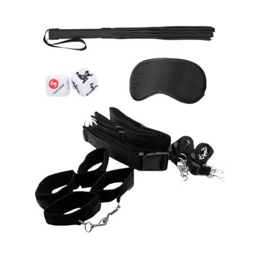 Black and white bondage restraint kit including adjustable belt, wrist and ankle cuffs, blindfold, flogger, and playful dice on white background.