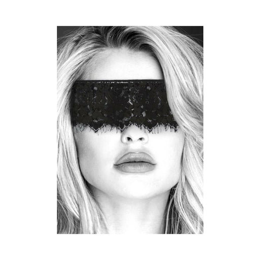 Close-up of a woman wearing a black lace eye mask with elastic straps covering her eyes.